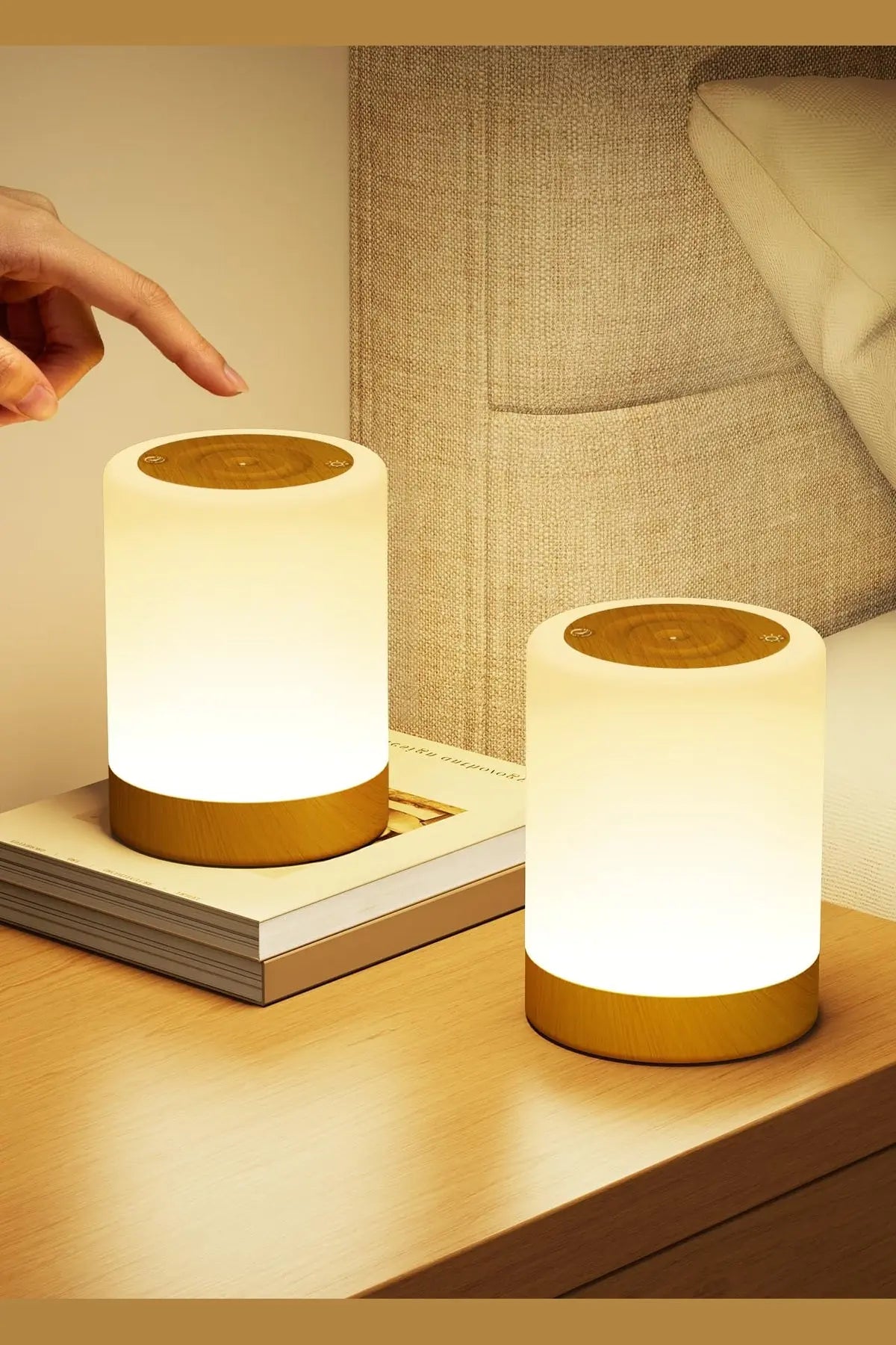 Deux lampes de chevet led tactiles cylindriques avec intensité variable et socles dorés sur surface en bois