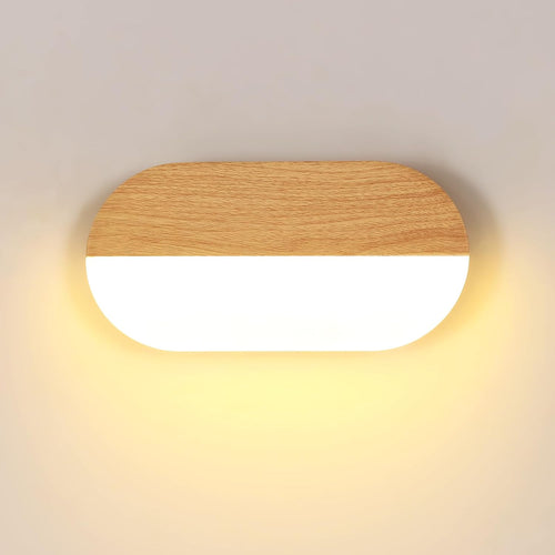 Vue frontale applique murale LED ovale bois clair grain fin sur fond crème, contraste acrylique translucide