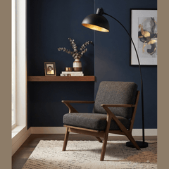 Lampadaire arqué noir et doré dans salon bleu marine style scandinave avec lumière chaude