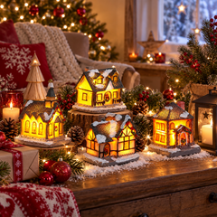 Village de Noël lumineux composé de quatre maisons miniatures LED éclairées en blanc chaud dans une décoration de Noël intérieure avec sapin, guirlande lumineuse, bougies et ornements festifs.